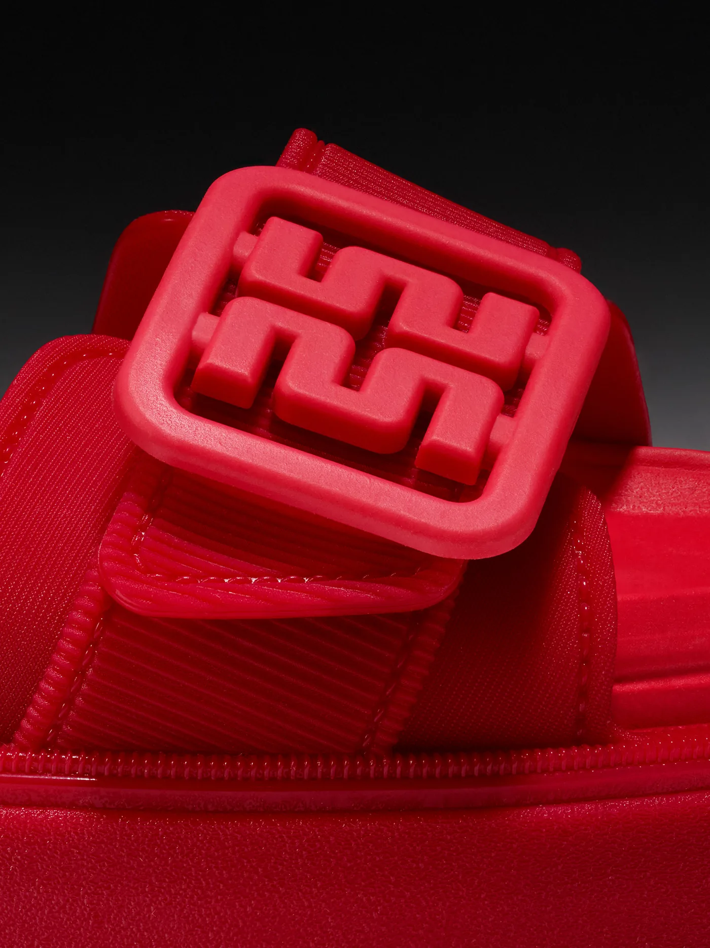 The monogram buckle on a red sandal, up close