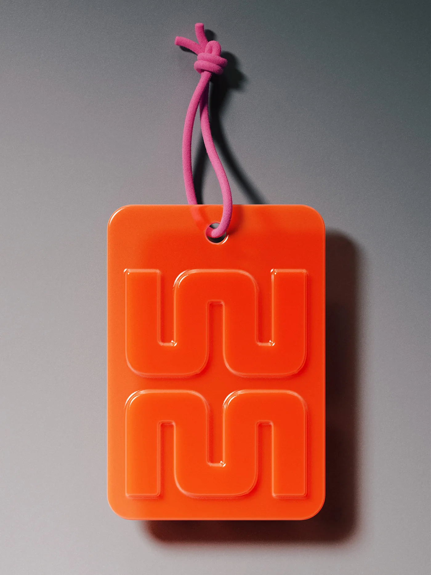 An orange monogram tag on a pink cord